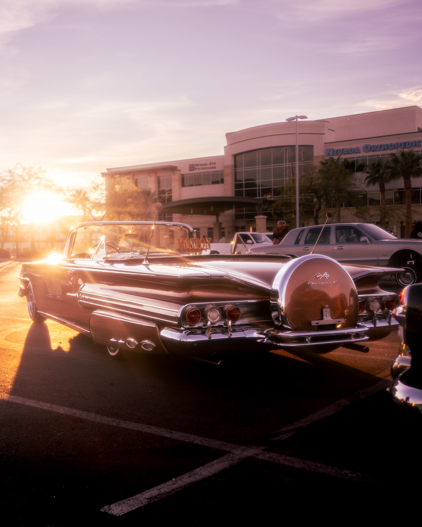 Classic Chevy with continental kit bathed in golden sunset light at car show